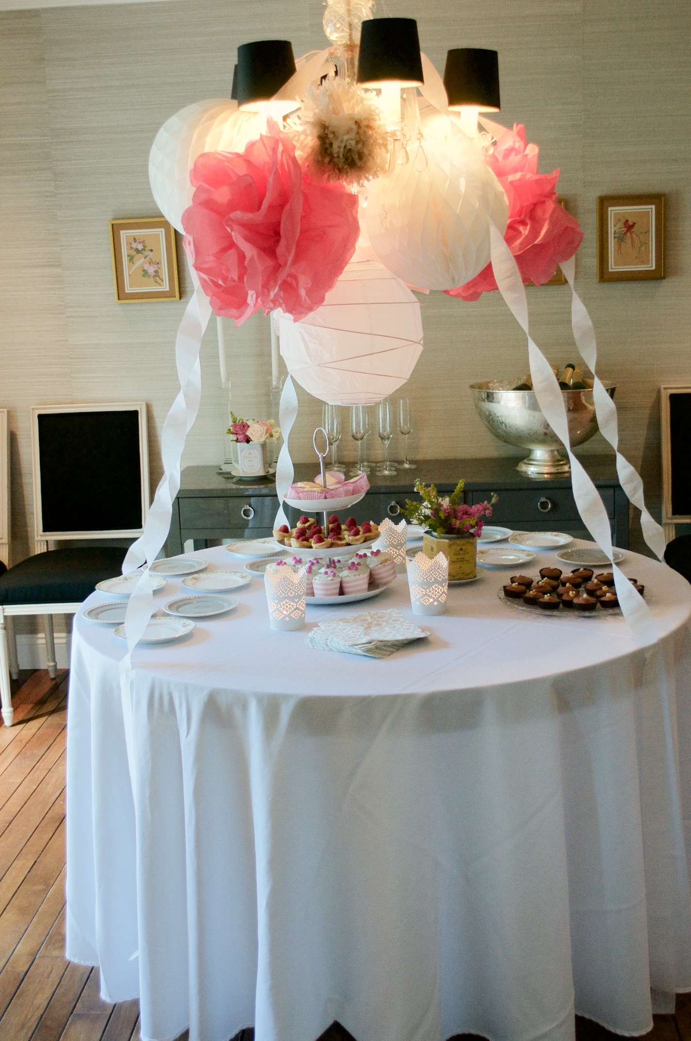 A pom pom and paper lantern display over the dessert table